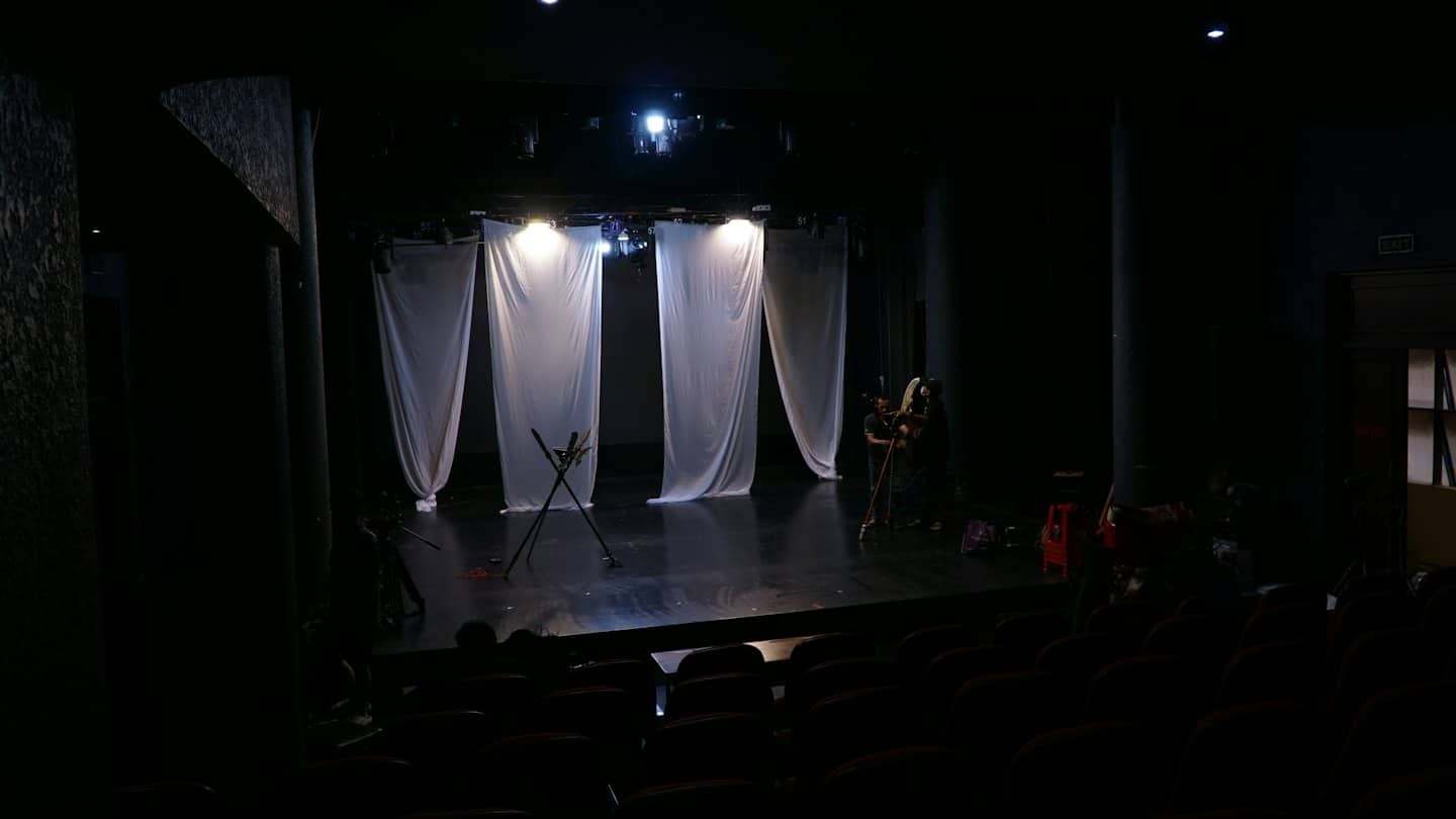 Membri della troupe teatrale che preparano la scenografia su un palcoscenico.